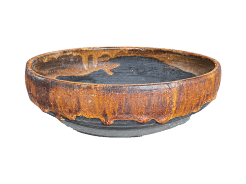 Alternate side of the amber and charcoal shallow pot showing flowing amber glaze over gray clay