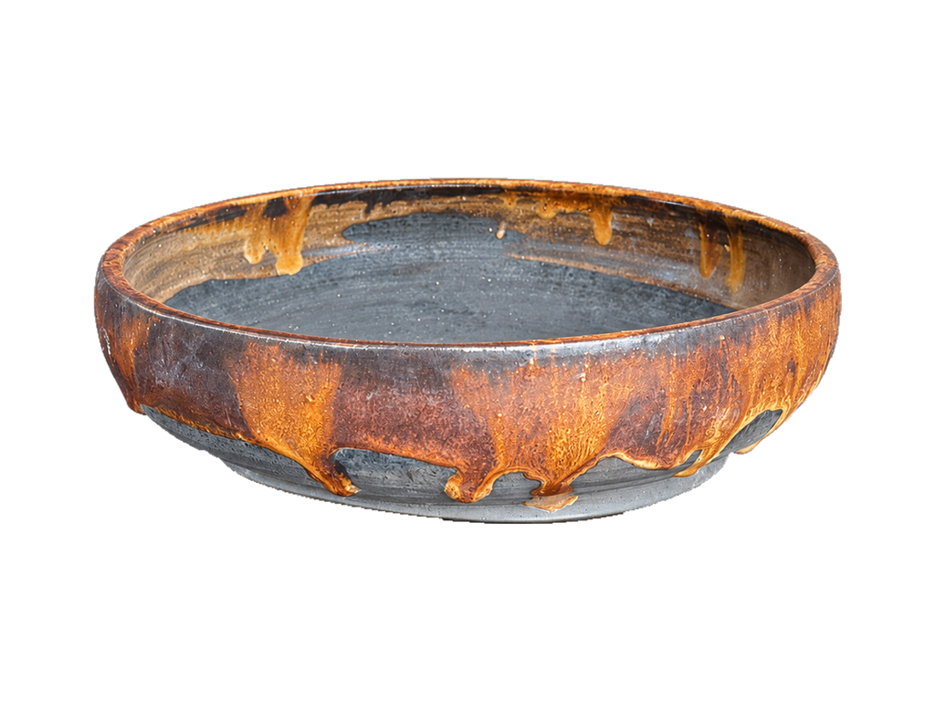 Amber and charcoal shallow round pot with amber glaze drips, a dark interior and gray foot ring