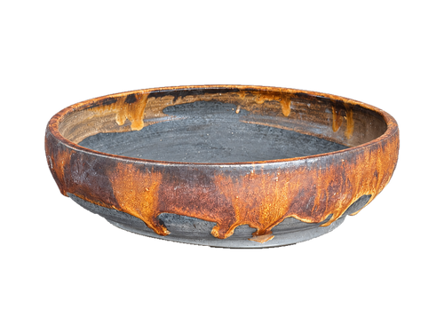 Amber and charcoal shallow round pot with amber glaze drips, a dark interior and gray foot ring