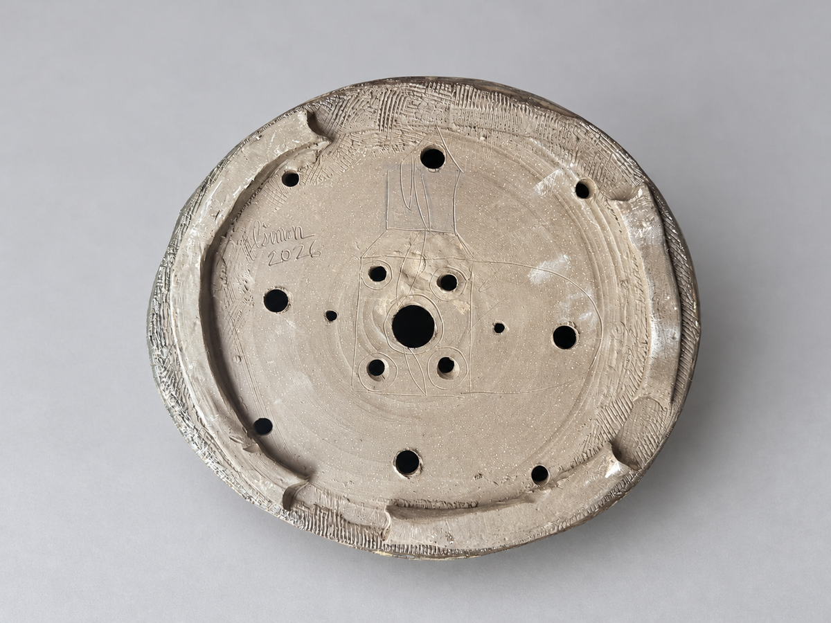 Underside of the blue and charcoal round pot showing its foot ring, holes and incised maker signature