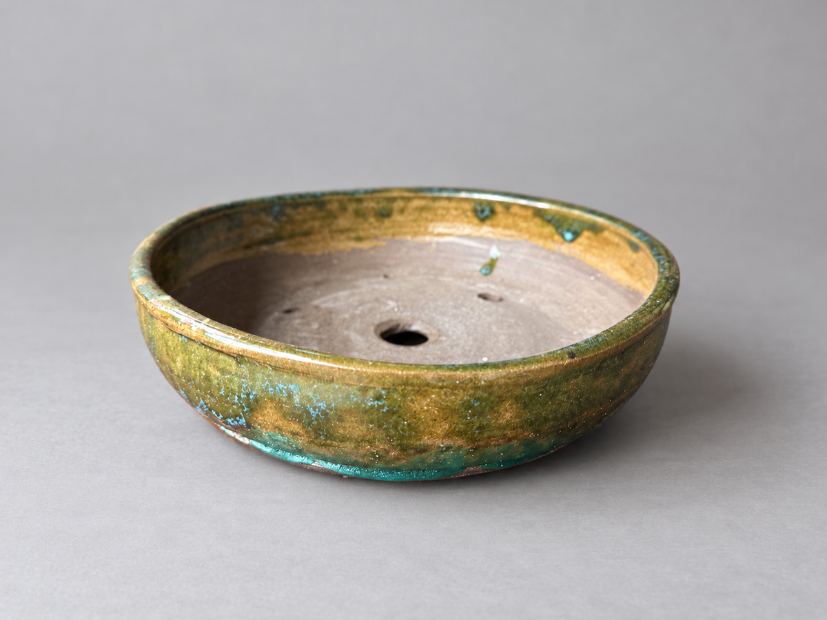 Alternate side view of the same amber and green shallow round ceramic pot
