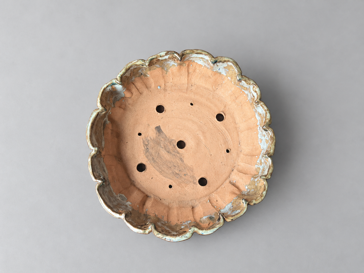 Top view of the scalloped pot showing its clay interior, drainage and wiring holes