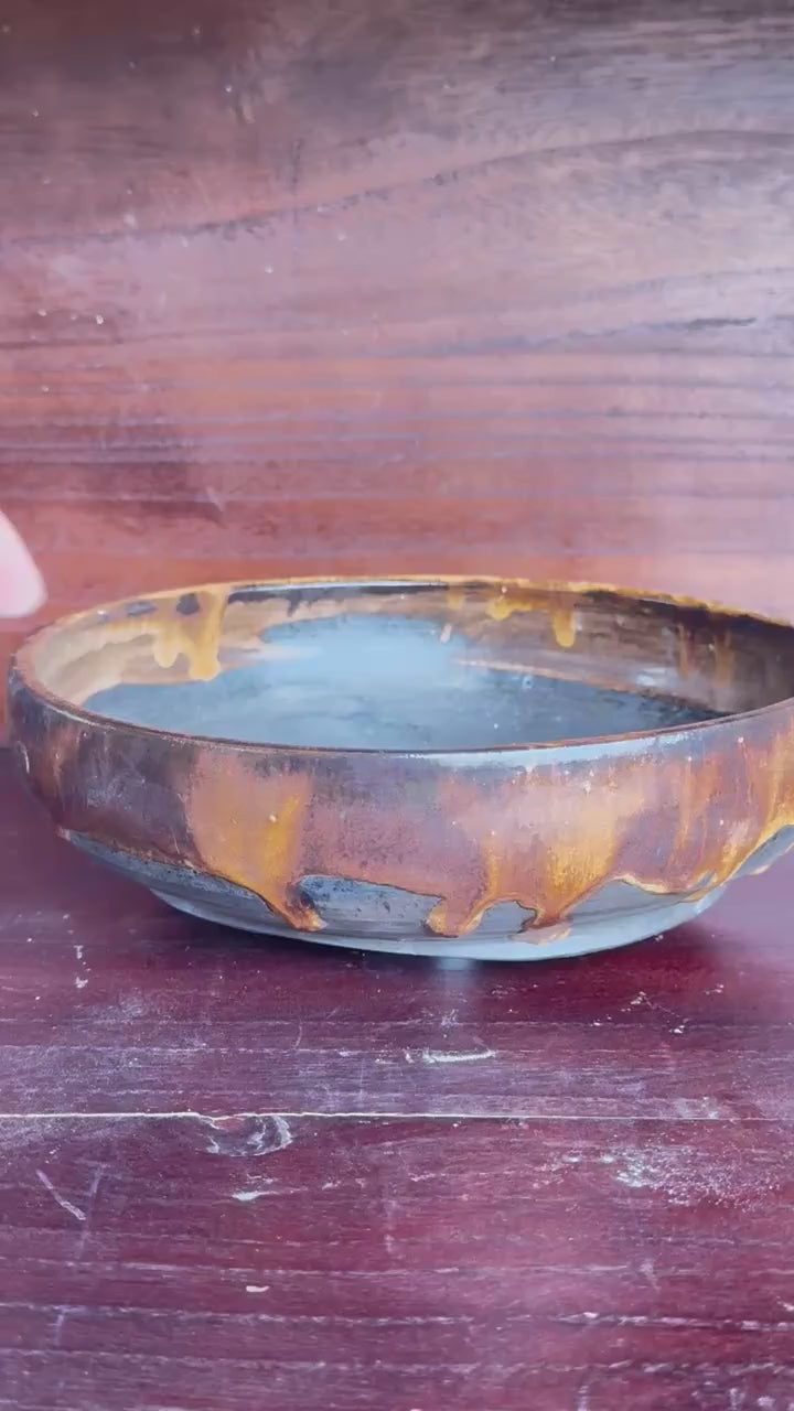 Rotating view of the amber and charcoal shallow round pot